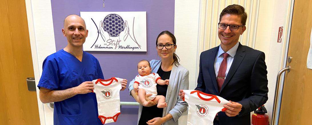 Von links: Chefarzt Kiriakos Savvidis, Christina mit Sara Atalay und Oberbürgermeister David Wittner präsentieren die neuen Bodys mit der Aufschrift "Echtes Rieser Kraterkind". 