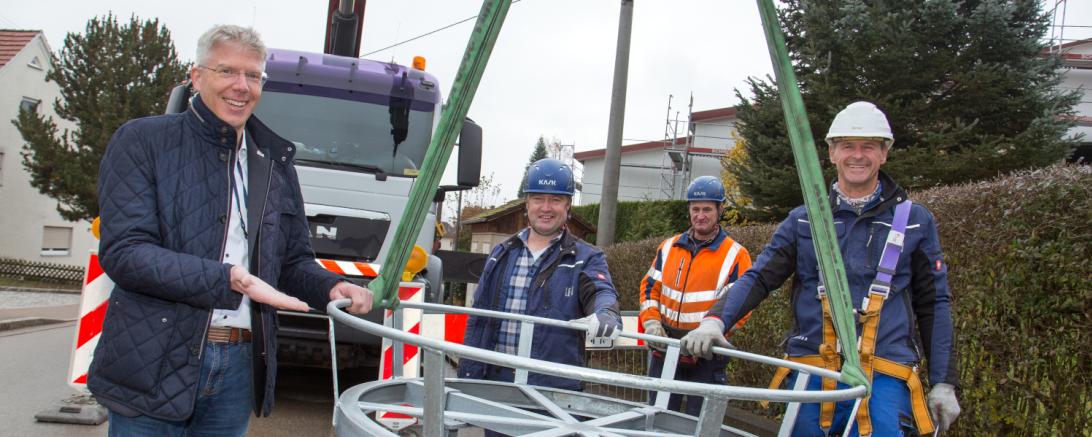 Veit Meggle und Arbeiter neben an Kran hängendem Metallkorb