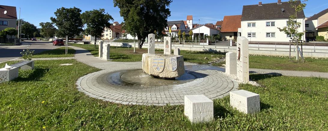 Auf den Stehlen des Dorfbrunnens ist die ereignisreiche Geschichte der Gemeinde abgebildet. 