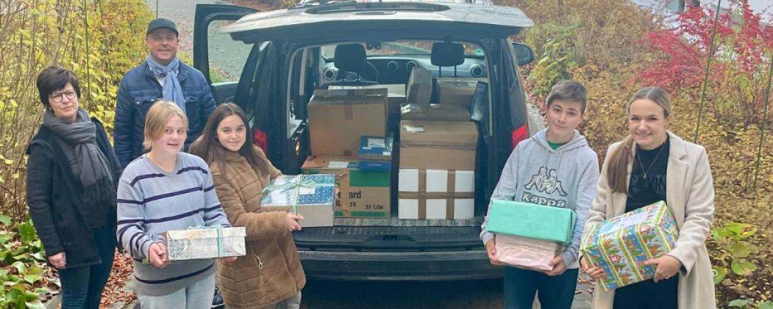 Sechs Personen laden Geschenke in Kofferraum