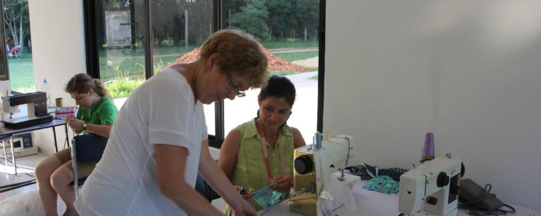 Auf dem Bild sieht man eine Frau an einer Nähmaschine.