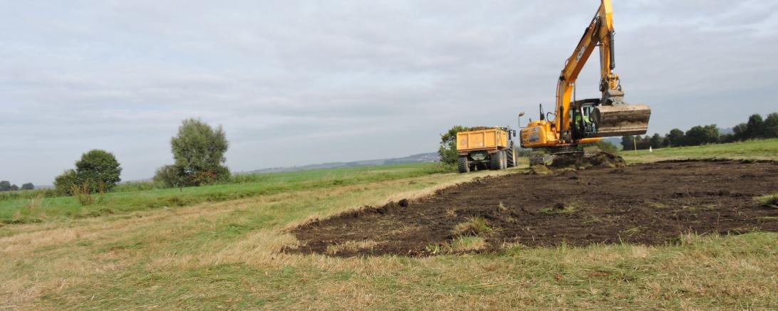 Auf dem Bild sieht man einen Bagger beim umgestalten der Äcker.