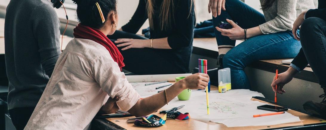 Menschen in um einen Tisch herum bei der Gruppenarbeit