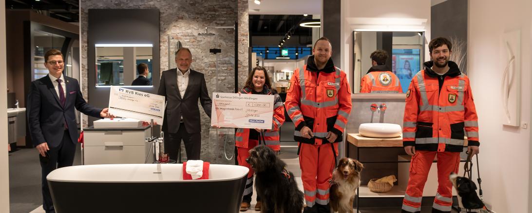 Das Bild von der Spendenübergabe in der neuen Bäderausstellung in Nördlingen zeigt von links Oberbürgermeister David Wittner mit dem Scheck für die Stiftung „Nördlinger Hilfe in Not“, Eisen-Fischer-Geschäftsführer Volker Baumgärtner sowie von der Rettungshundestaffel Ries Ausbilderin Patricia Schlosser, den 2. Vorsitzenden und Gruppenführer Marcel Neubauer und Hundeführer Fabian Altmann, jeweils mit ihren Rettungshunden Lotte, Max und Emma.  