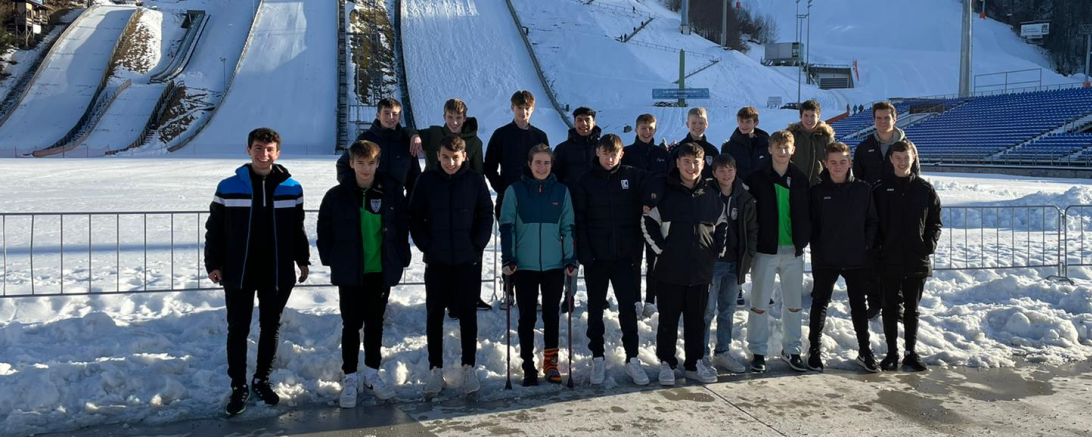 Das Bild zeigt die U15 mit den Trainern Simon Lösch (ganz links) und Fabian Schmidt (rechts oben) vor der Olympiaschanze. 