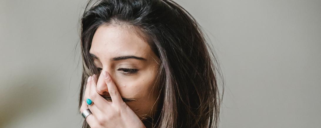Frau hält sich die Hand vors Gesicht