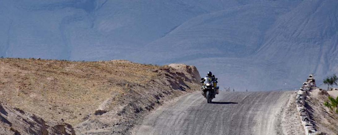 Auf dem Bild ist ein Motorradfahrer auf einer einsamen Straße zu sehen.