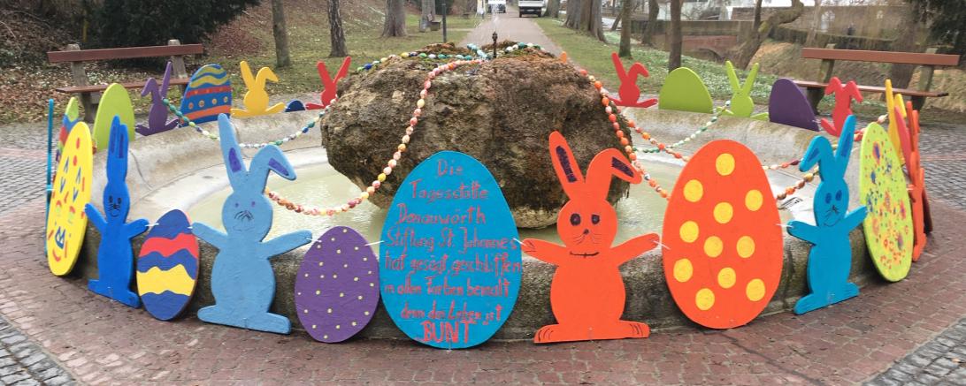 Ein mit bemalten Hasen und Ostereiern aus OSB-Platten verzierter Springbrunnen.
