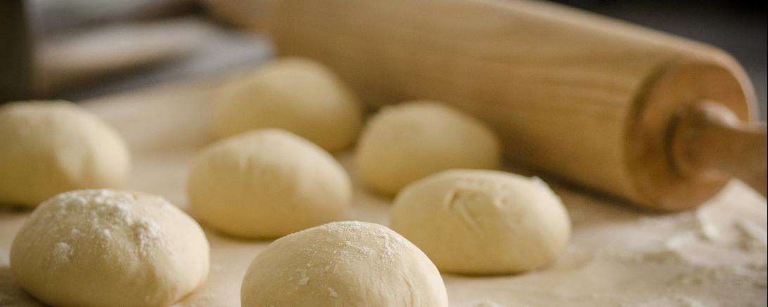 Zu sehen sind ein Nudelholz und einige Teigklumpen.