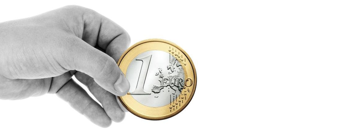 Eine Hand die eine Euromünze hält.