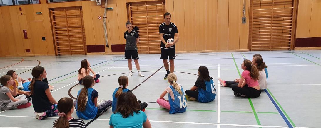 Das Bild zeigt Sarah Eberhardt und Markus Klaus, die den Mädchen gerade etwas zeigen