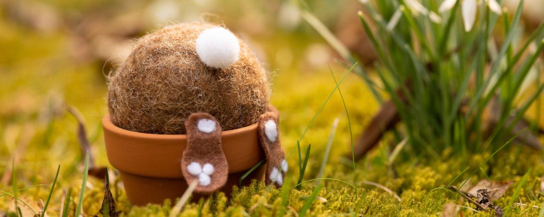 Zu sehen ist ein Hase aus Filz, welcher Kopfüber in einem Blumentopf steckt. 