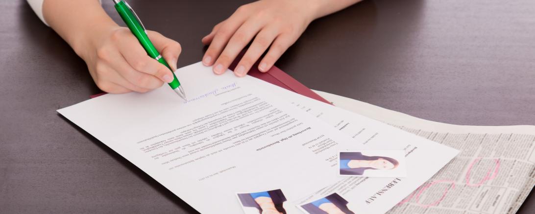 Frau setzt Unterschrift unter ihr Bewerbungsschreiben