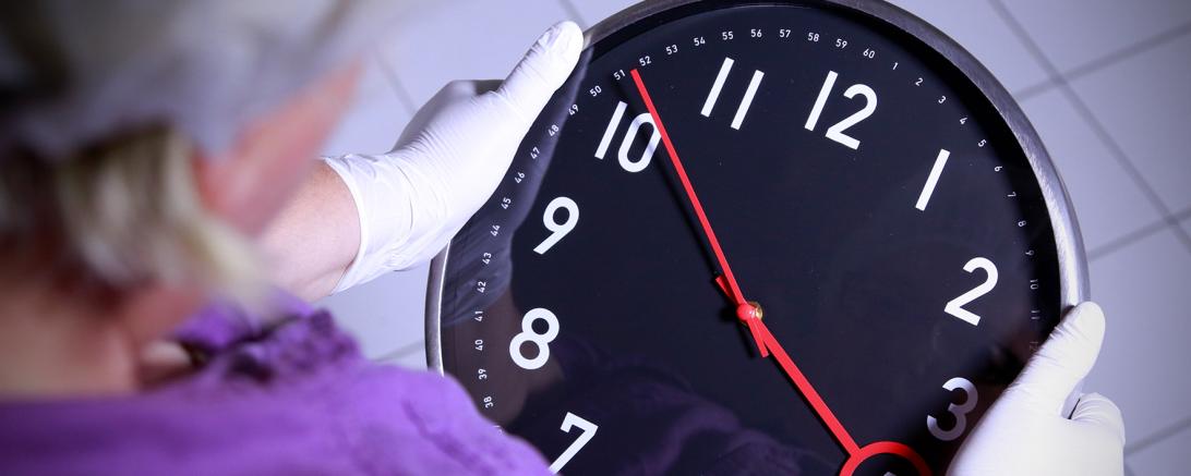 Zu sehen ist eine Person, welche eine Uhr in den Händen hält.