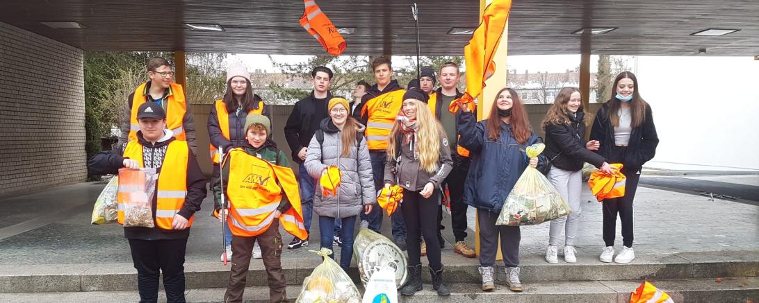Zu sehen ist die Klasse 8 b nach der Müllsammelaktion in Warnwesten mit dem gesammelten Müll. 