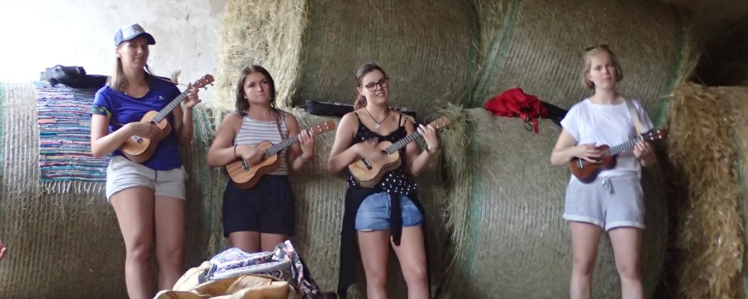 Vier junge Frauen mit Ukulele vor Heuballen