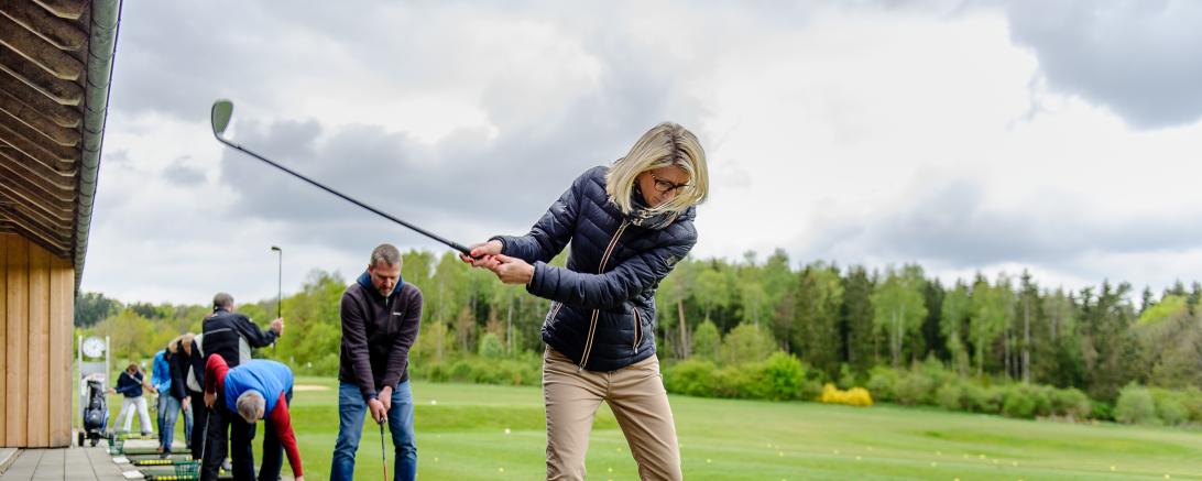 Das Bild zeigt Personen beim Golf spielen.