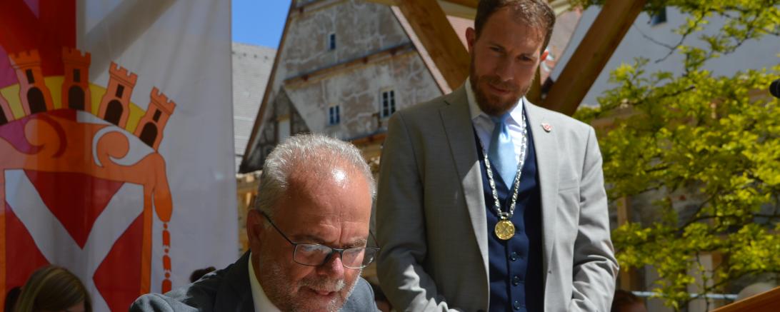 Zu sehen sind Dr. Erwin Lohner während er im Goldenen Buch unterschreibt und Thomas Heydecker.