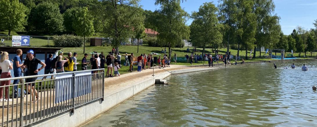 Zu sehen sind Sportler und Zuschauer beim Wemdinger Triathlon am Waldsee. 