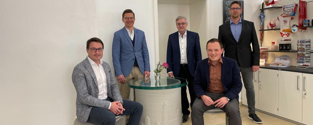 Fünf Personen auf Betonsitzgruppe. 