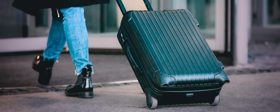 Zu sehen ist eine Person mit einem Koffer. 