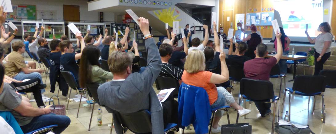 Viele Menschen bei einer Versammlung wie sie ihre Hände heben.