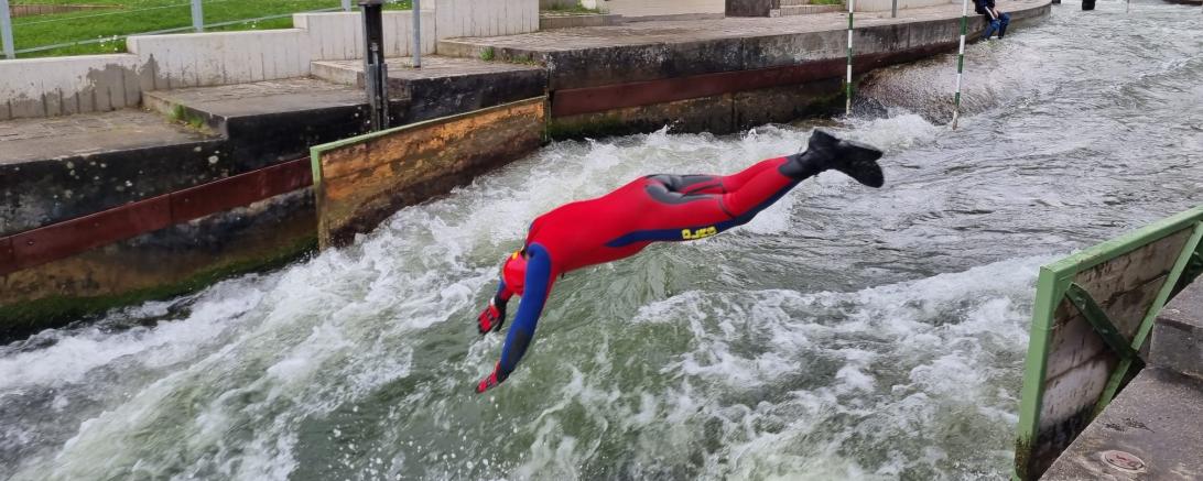 Zu sehen ist eine Person, die in einen Kanal springt. 