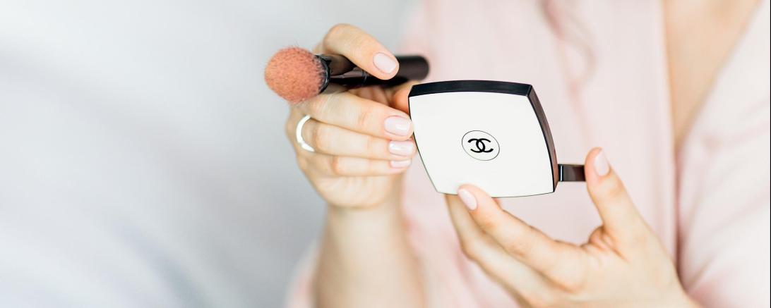 Das Bild zeigt eine Frau, die gerade Make-up aufträgt