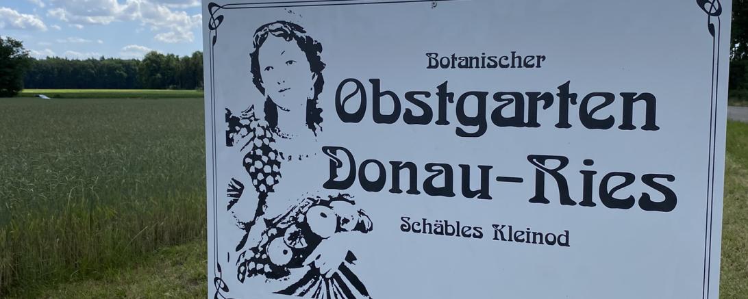Zu sehen ist ein Schild mit der Aufschrift "Botanischer Obstgarten Donau-Ries Schäbles Kleinod".