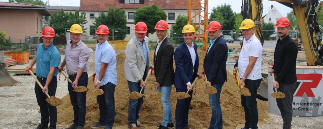 Auf dem Bild zu sehen beim Spatenstich für das Gebäude am Marktplatz Nord in Asbach-Bäumenheim (von links): Otto Uhl (Gemeinderat), Stefan Reicherzer (Gemeinderat), Lars Meier (Gemeinderat), Hansrobert Schimmer (Gemeinderat), Stefan Bissinger (Leitung Bauamt), Ulrich Reitenberger (Geschäftsführer Ulrich Reitenberger Bau GmbH), Martin Paninka (Bürgermeister), Georg Feistle (Projektleiter) und Maurice Wiedenmann (Projektentwicklung). 
