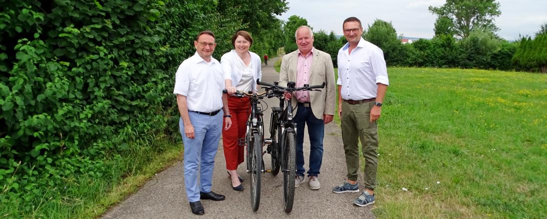 Ulrich Lange, Claudia Marb, Georg Stoller und Alexander Wolfinger mit Fahrrädern auf einem Radweg. 