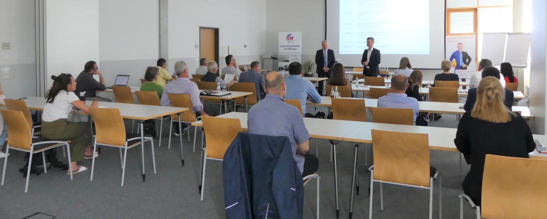 Zu sehen sind mehrere Personen bei einem Vortrag. 