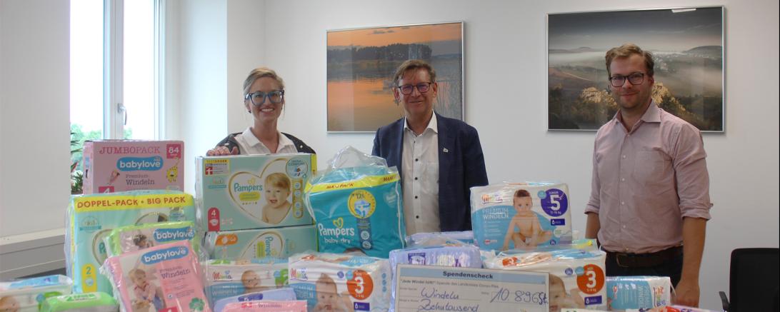 Karin Brechenmacher, Stefan Rößle und Klemens Heininger hinter einem Stapel Windeln. 