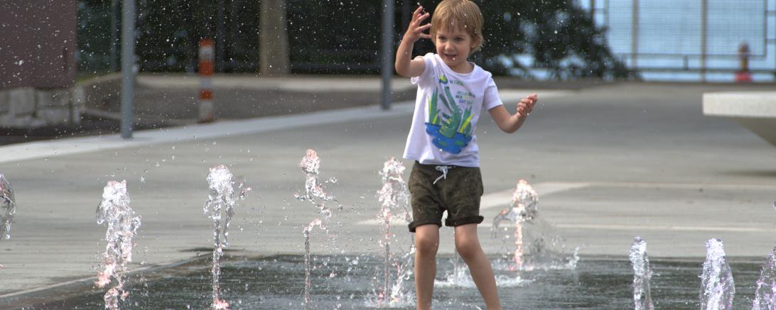 Kind spielt an Bodensprudelanlage/Wasserspiel