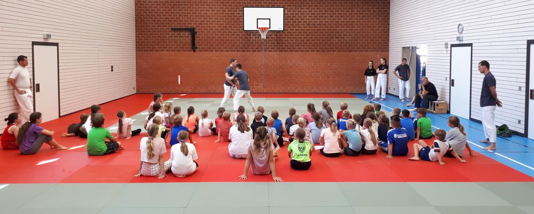 Das Bild zeigt die Betreuer*innen und die Kinder des Ferienprogrammes in der Turnhalle in Kleinerdlingen.