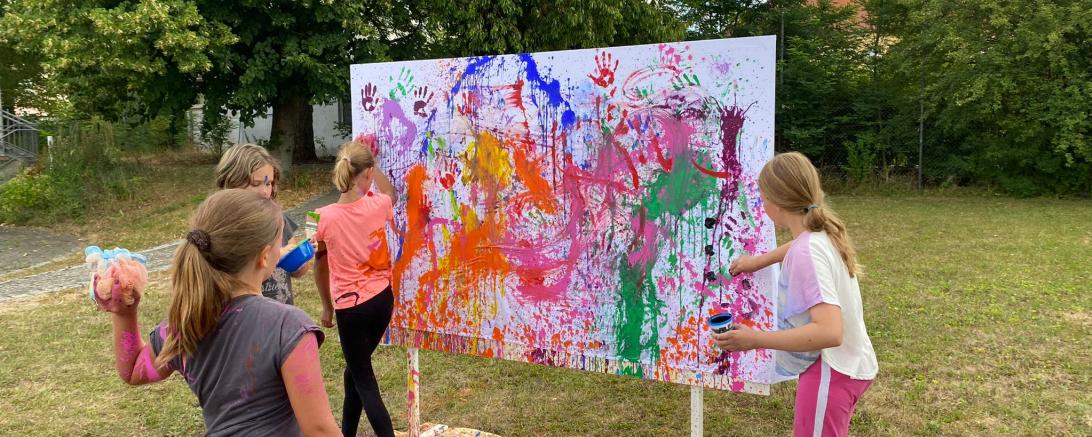 Das Bild zeigt Teilnehmende des Ferienprogramms beim Action Painting.