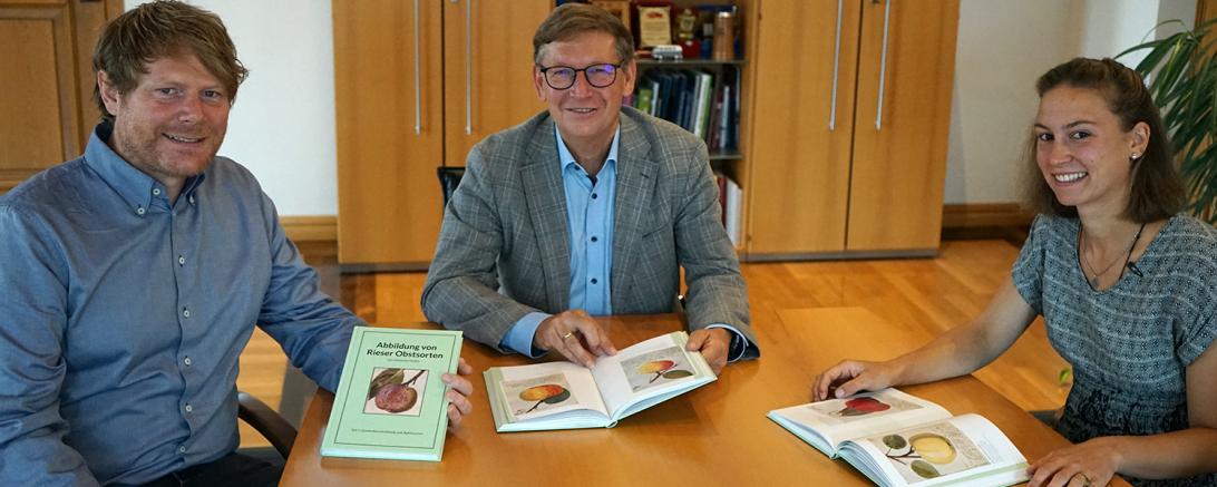 Die beiden Kreisfachberater für Gartenkultur und Landespflege Paul Buß und Sophia Och stellen Landrat Stefan Rößle (Bildmitte) das neue und doch auch alte Buch "Abbildung von Rieser Obstsorten" vor.