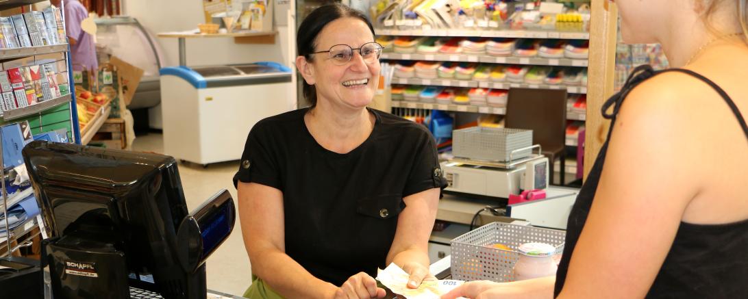 Simone Gerstmeyr zahlt einer Kundin nach dem Einkauf 200 Euro Bargeld aus. 