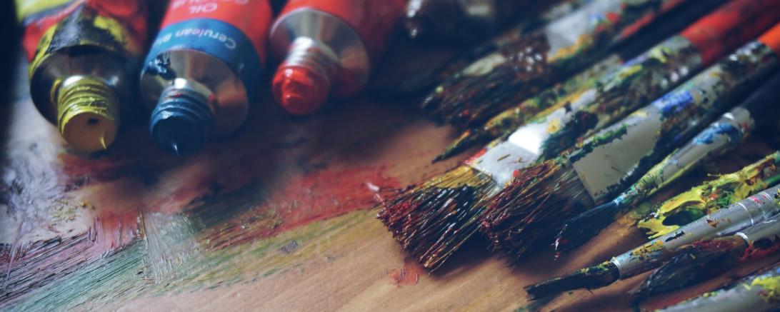 Das Bild zeigt Acrylfarben und Pinsel.