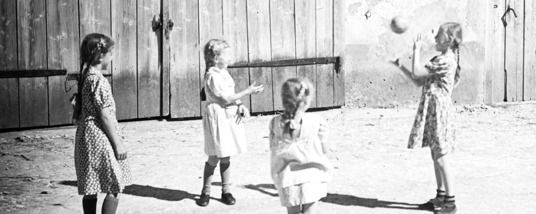 Das schwarz-weiß-Bild zeigt ein paar Mädchen die Ball spielen.