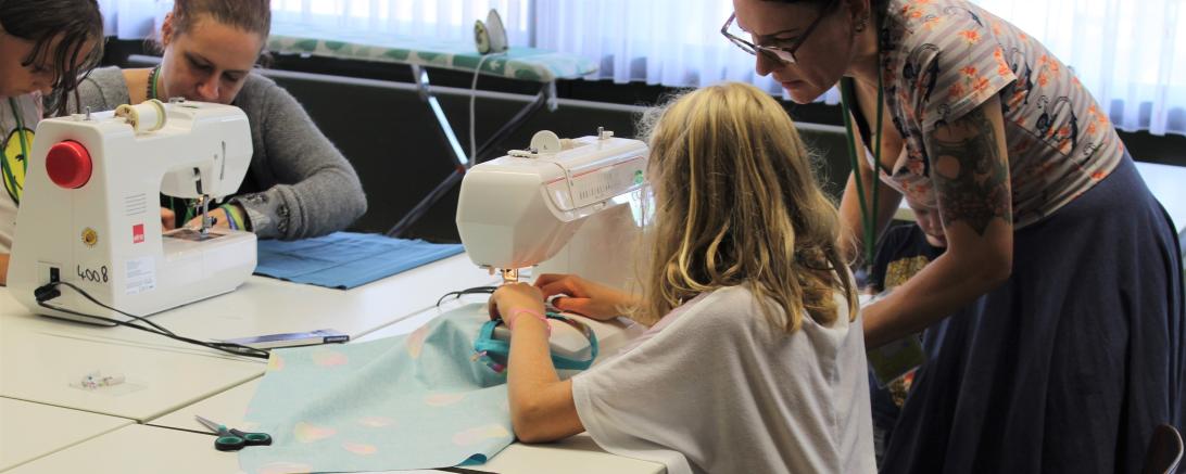 Das Bild zeigt ein Kind beim Nähen in der Schneiderei der Spielstadt.