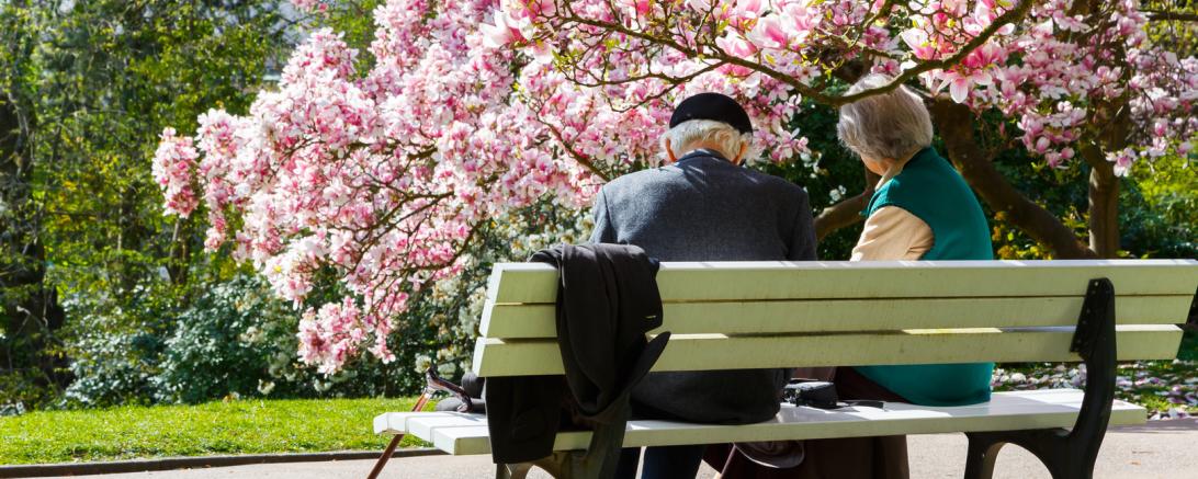Alte Menschen sitzen auf einer Parkbank. 