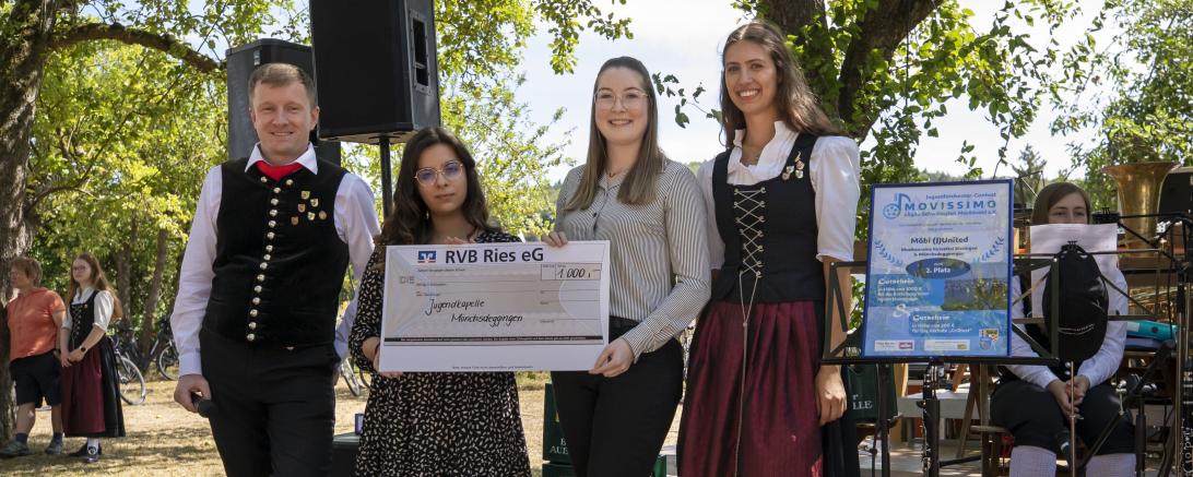 Das Bild zeigt Mitarbeiter*innen der Raiffeisen Volksbank Ries und Musiker*innen der Jugendkapelle Mönchsdeggingen bei der Spendenübergabe. 