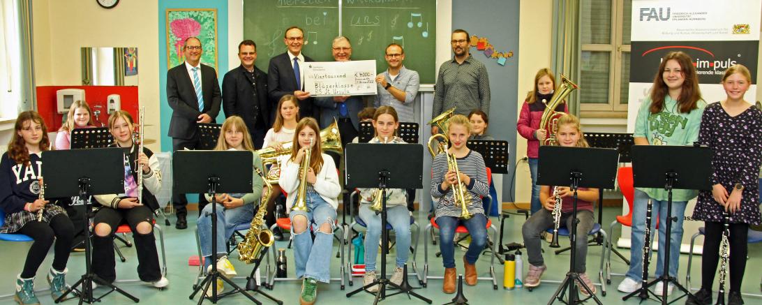 Unser Bild zeigt mit 14 Schülerinnen der Bläserklasse von links Schulwerk-Direktor Peter Kosak, OB Jürgen Sorré, Sparkassendirektor Johann Natzer, Realschuldirektor Peter Müller, den Leiter der Bläserklasse Tobias Freißler und den klasse.im.puls-Projektmanager der Friedrich-Alexander-Universität Erlangen-Nürnberg, Christoph Utz.
