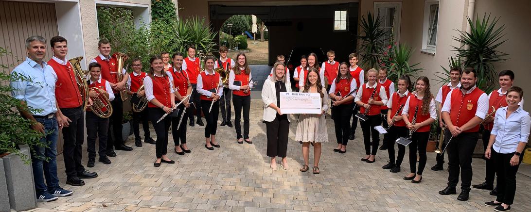 Das Bild zeigt die Musikerinnen und Musiker mit ihrem Dirigenten Fabian Grimm und Jugendleiterin Karin Wolf (rechts vorne). Den Scheck überreichten Lisa Gerstmeyr (Mitte, links) und Maresa Nagler von der RVB Ries.