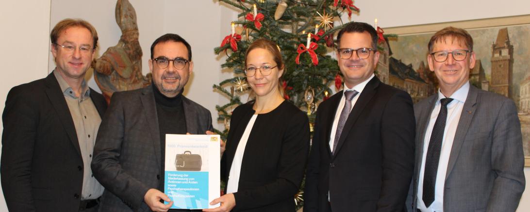 Gesundheitsminister Klaus Holetschek (2.v.l.) übergibt im Beisan von MdL Wolfgang Fackler (l.), OB Jürgen Sorré (2.v.r.) und Landrat Stefan Rößle (r.) den 1000. Förderbescheid an Dr. Katharina Ehrenberg. 