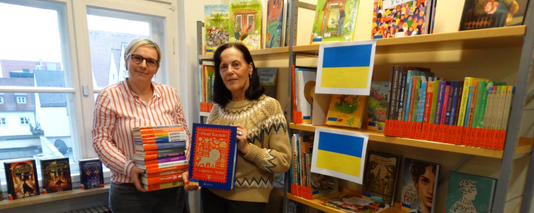 Das Bild zeigt die Familienbeauftragte und Bündniskoordinatorin Ursula Leinfelder (links) und die Leiterin der Stadtbibliothek Donauwörth Evelyn Leippert-Kutzner (rechts) bei der Übergabe der ukrainischen Kinder- und Jugendbücher.