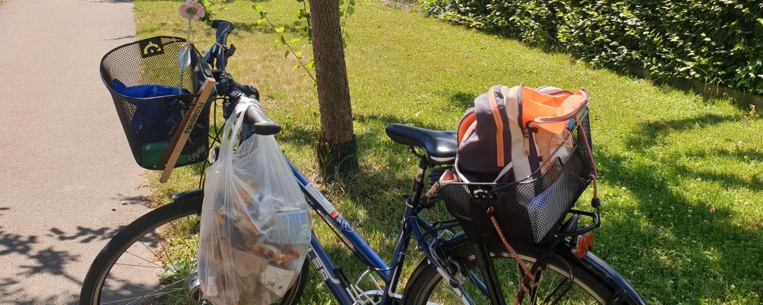 Das Bild zeigt ein Fahrrad mit Tüten, in welchen sich bereits gesammelter Müll befindet.