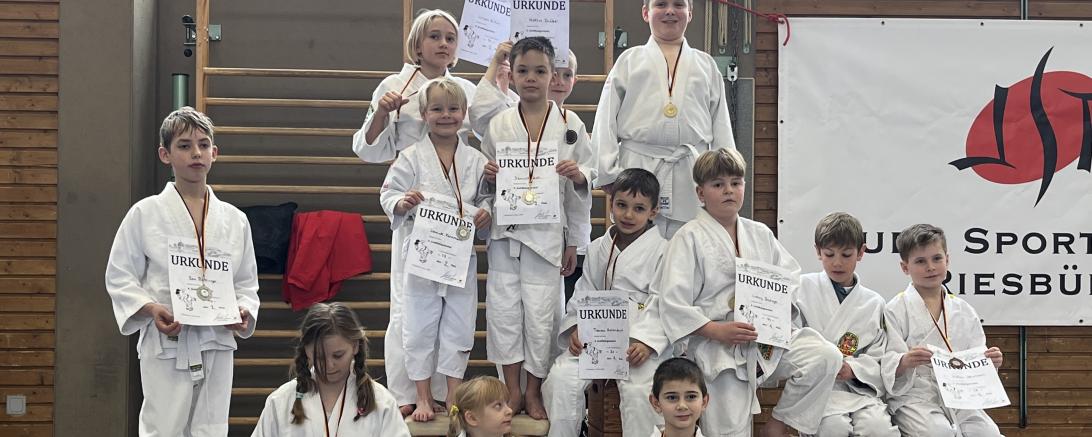 Das Bild zeigt von hinten links nach rechts 3. Reihe Juliana Hilkert, Hektor Gröber, Jonas Meier 2. Reihe Jannick Kornmann, Dominik Holl, Fabian Hebenstreit, Ludwig Bretzger, Lars Moßhammer, Lukas Jaumann 1. Reihe Ben Röttinger, Abby Maier, Sunny Maier, Dima Dutengefer. Es fehlen Niklas Slavik und Tim Schürmann. 