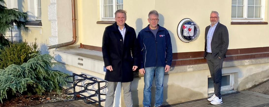 Benedikt Bigler (Allianz), Tobias Streitwieser (BRK Wemding) und Bernd Huber (Allianz) vor dem neuen Defibrillator in Wemding.